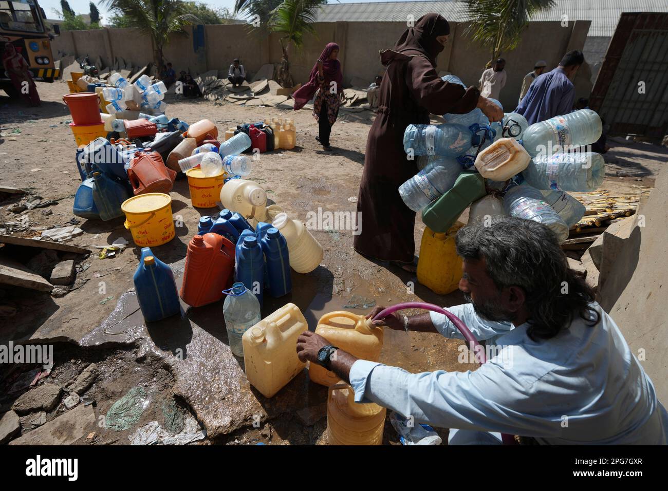 People get drinking water from a water collecting point at a slum area