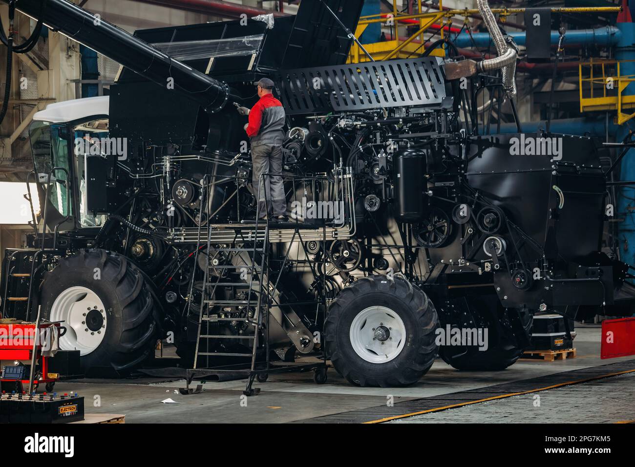 Industrial worker assembles agricultural harvester in workshop. Stock Photo