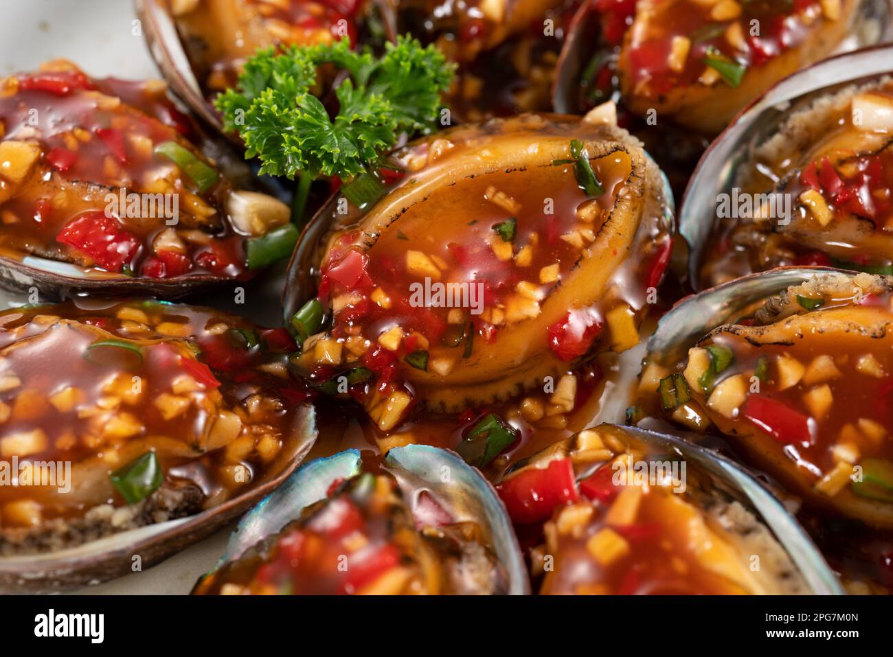 Delicious steamed abalone with spicy tomato sauce, Taiwanese five flavor sauce on wooden table background. Stock Photo