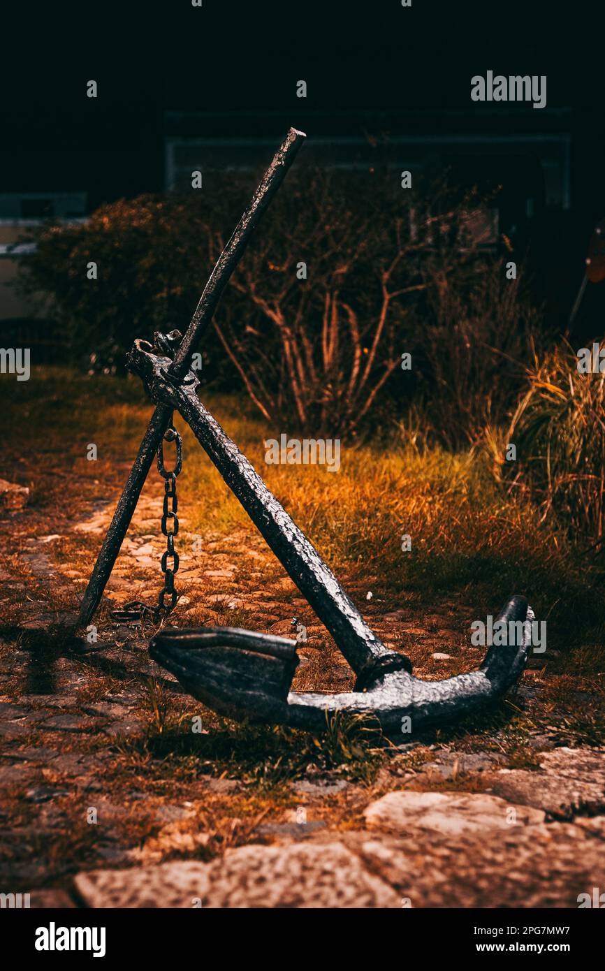 A metal anchor in the grass of a backyard at night, illuminated by a soft, ambient light. Stock Photo