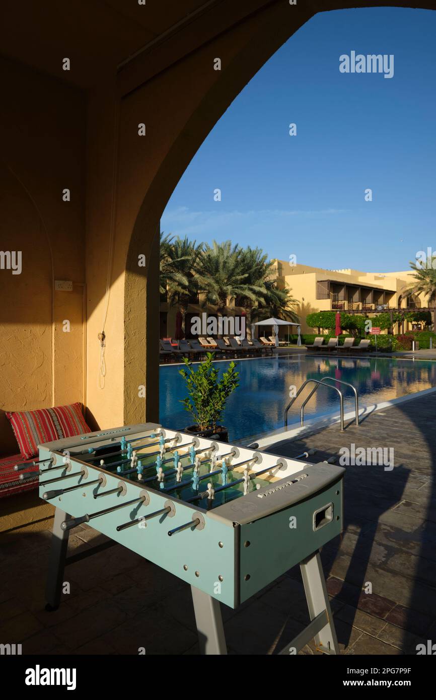 A quiet foosball game table with swimming pool in the background. At