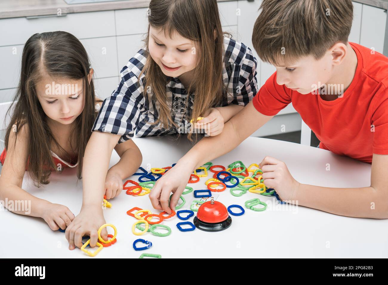 Smiling, pensive children of boy and girls connecting colorful chain ...
