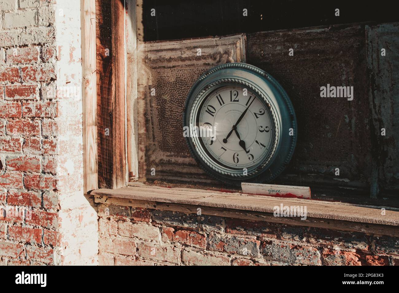 A classic antique pendulum clock mounted on a brick wall in an aged building Stock Photo