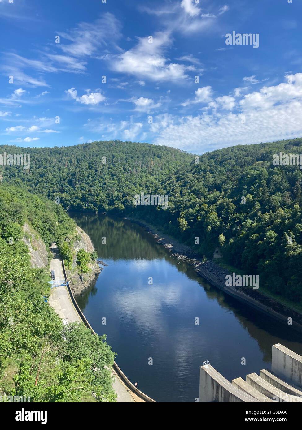 An aerial view of a large dam, showcasing the body of water held back by the structure, as well as its impressive size from the side Stock Photo