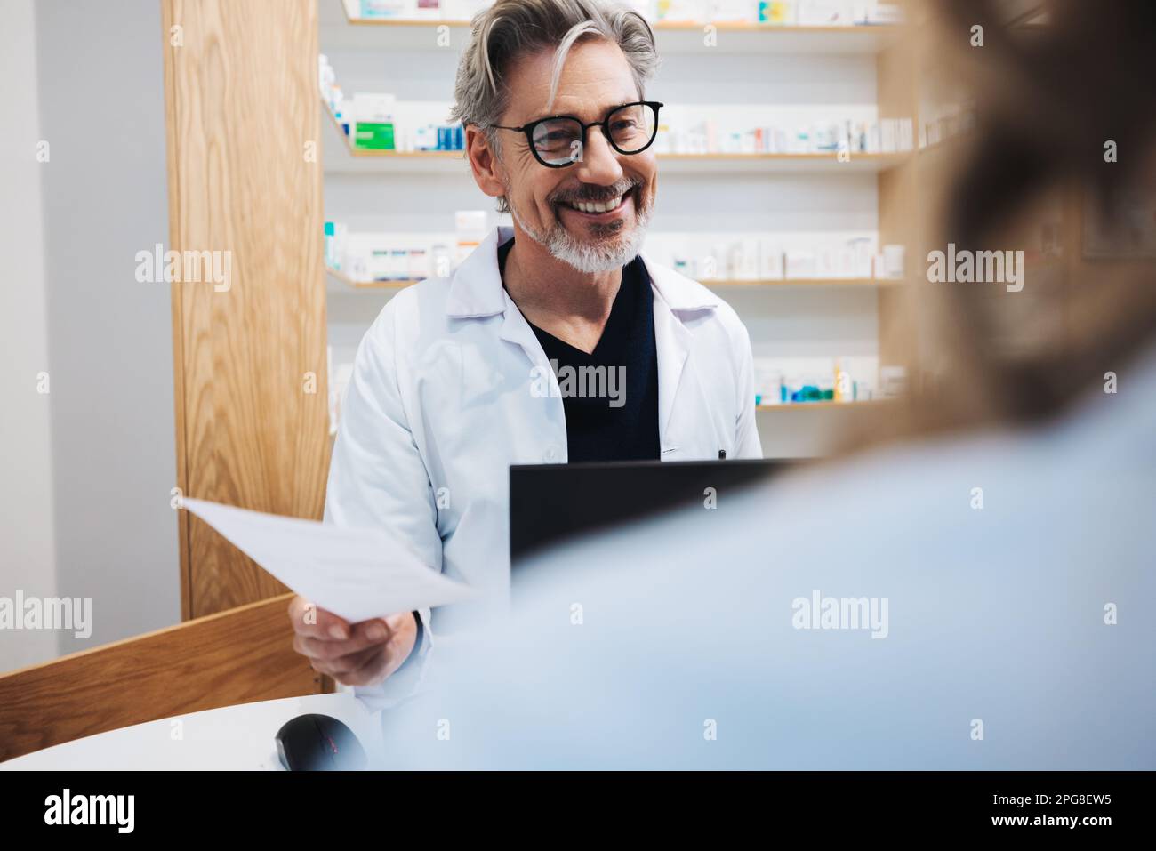Senior pharmacist assisting a patient over the counter in a chemist