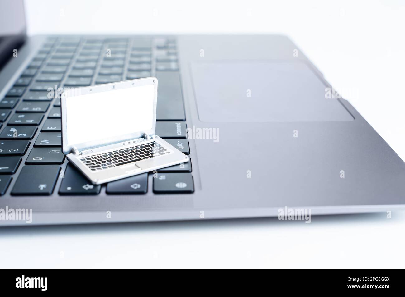 Miniature toy laptop placed on a top of the keyboard of a fullsized