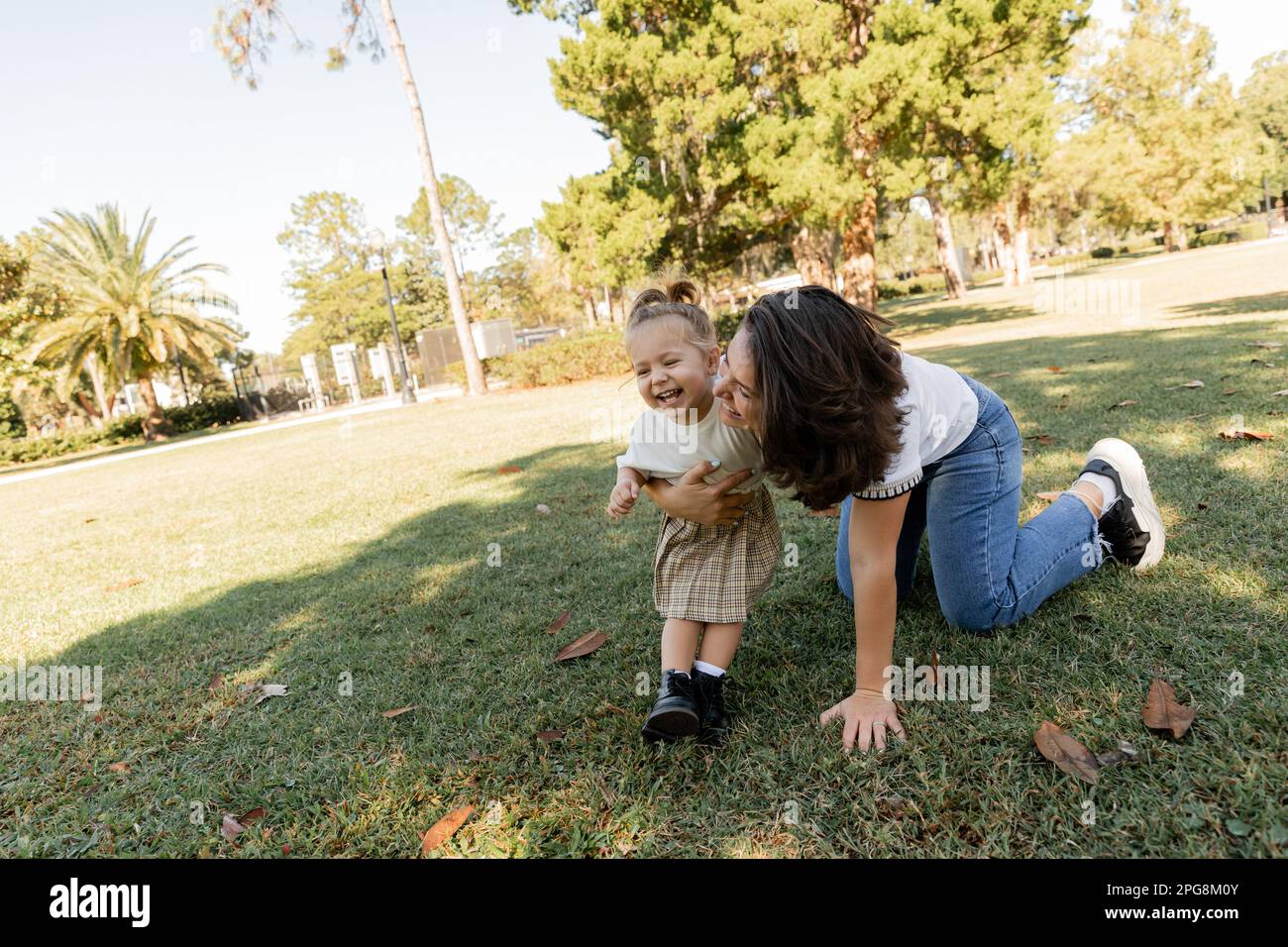 toddler girl laughing with happy mother while playing together in Miami park,stock image Stock Photo
