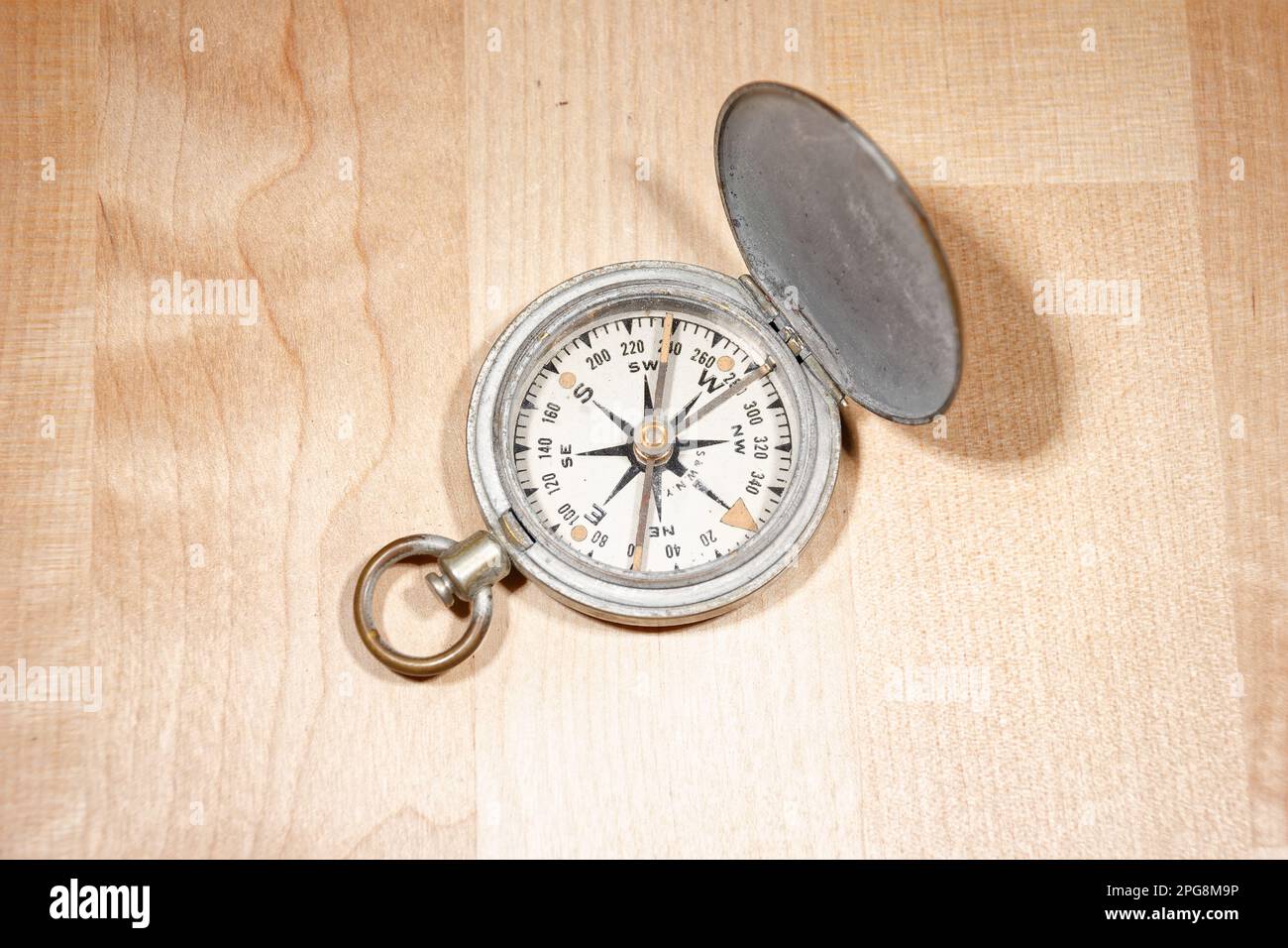 Open old vintage compass on wooden table Stock Photo