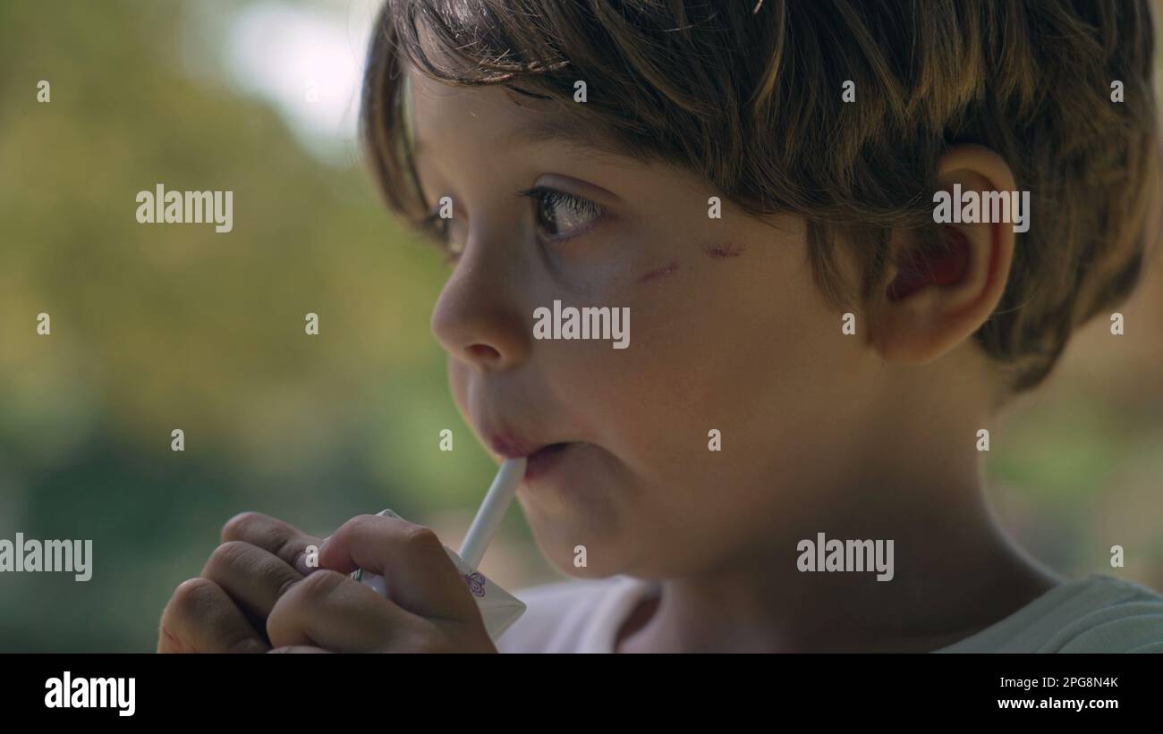 Portrait of a child drinking juice from straw from carton box outside