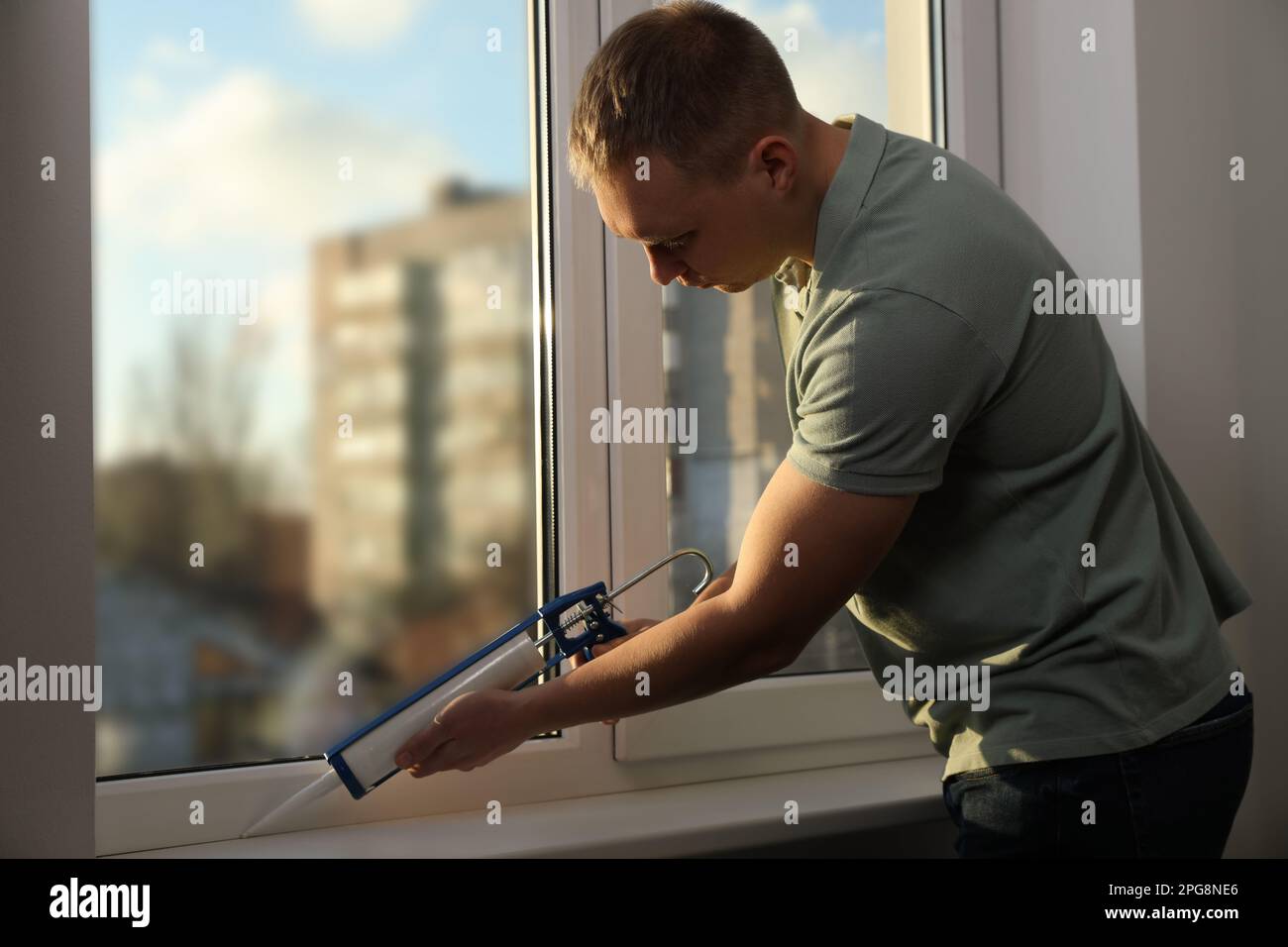 Construction worker sealing window with caulk indoors Stock Photo