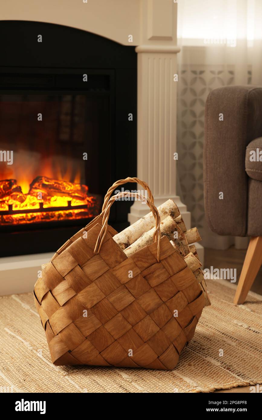 Wicker basket with wood near fireplace in room Stock Photo Alamy