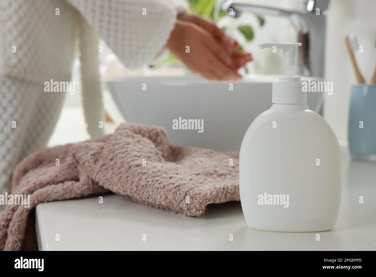 Woman washing hands with liquid soap in bathroom, focus on dispenser. Space for text Stock Photo