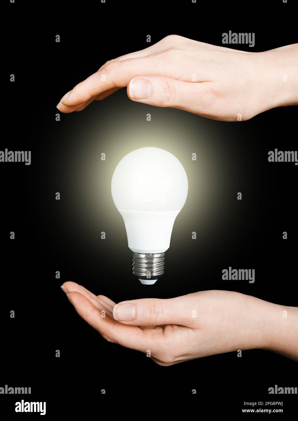 glowing led light bulb in hands of woman on black background, energy saving, global economy concept, electricity problems, power outages due to destru Stock Photo