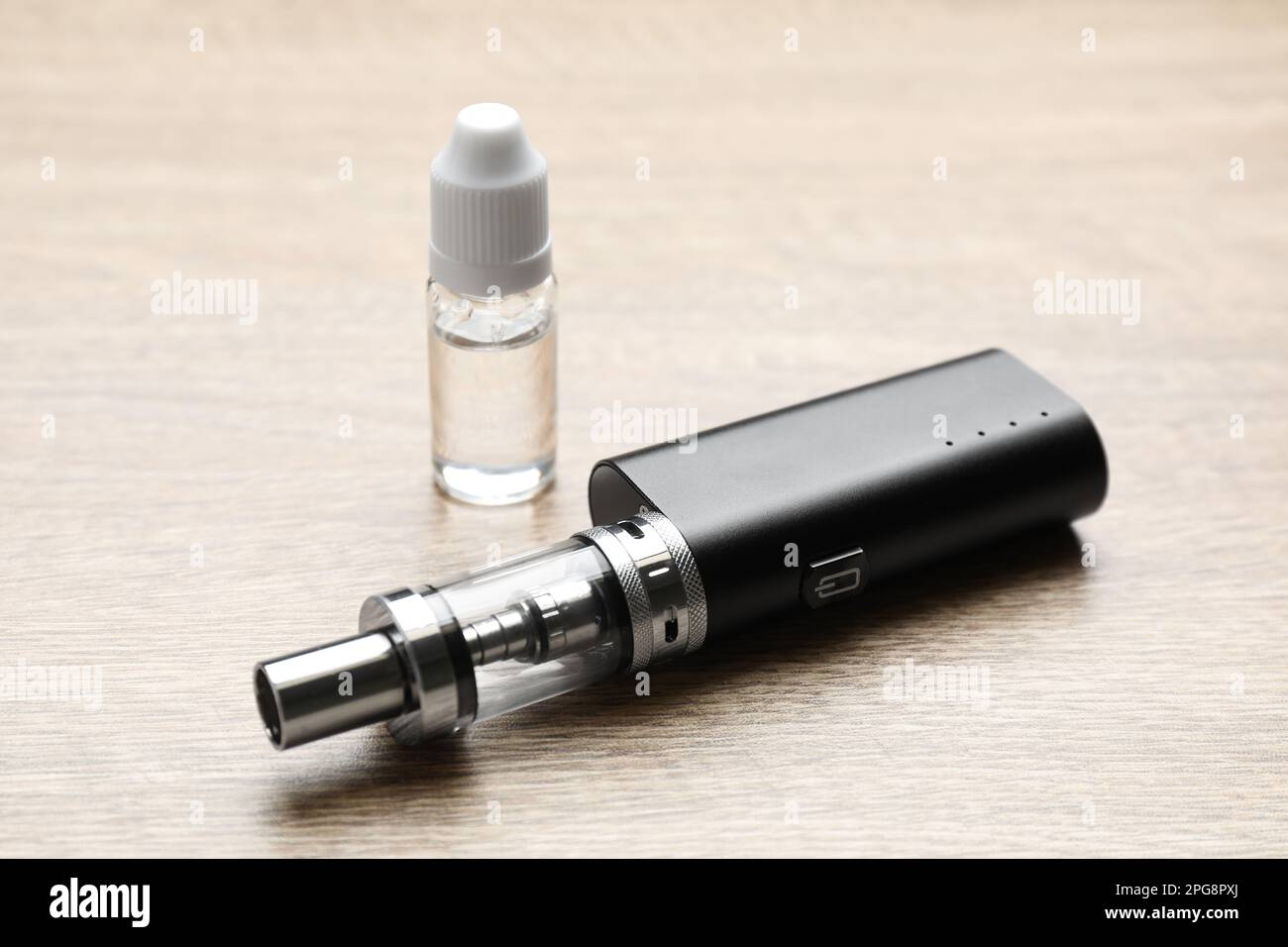 Electronic cigarette and vaping liquid on wooden table. Smoking