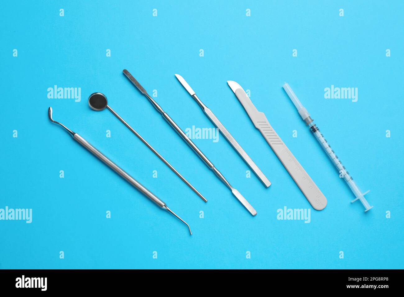 Set of different dentist's tools and syringe on light blue background