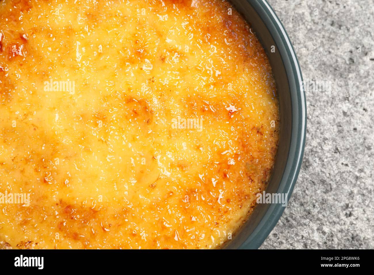 Delicious creme brulee in ceramic ramekin on grey table, closeup Stock