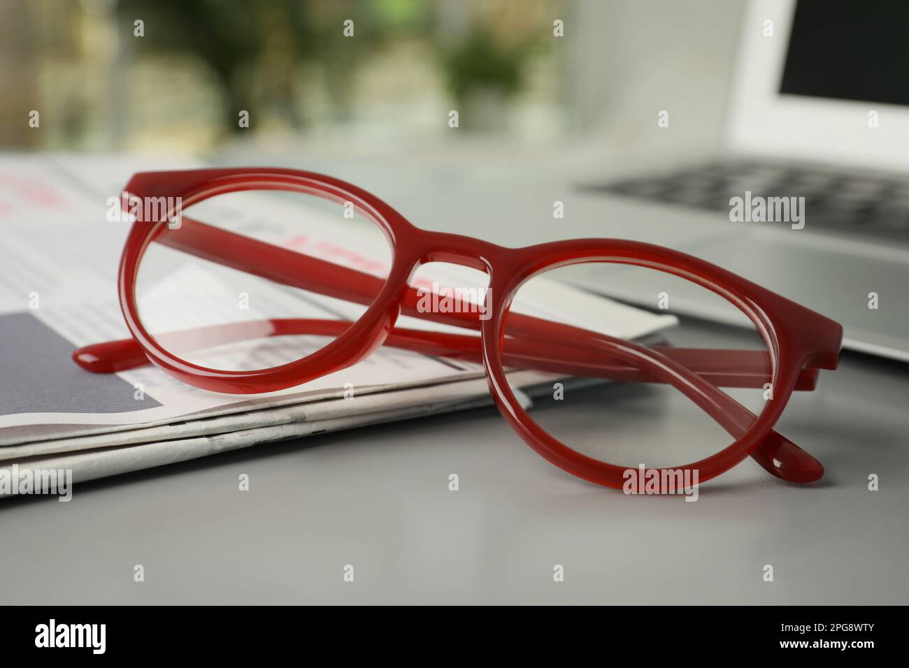 Newspaper and glasses on grey table, closeup Stock Photo