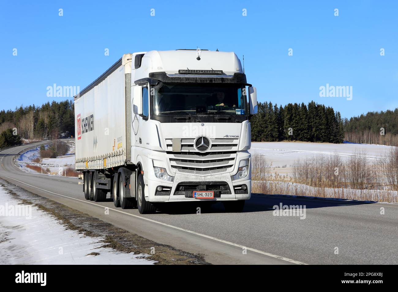 White Mercedes-Benz Actros 2653 truck pulls DB Schenker semi trailer along highway on a sunny day of early spring. Salo, Finland. March 9, 2023. Stock Photo