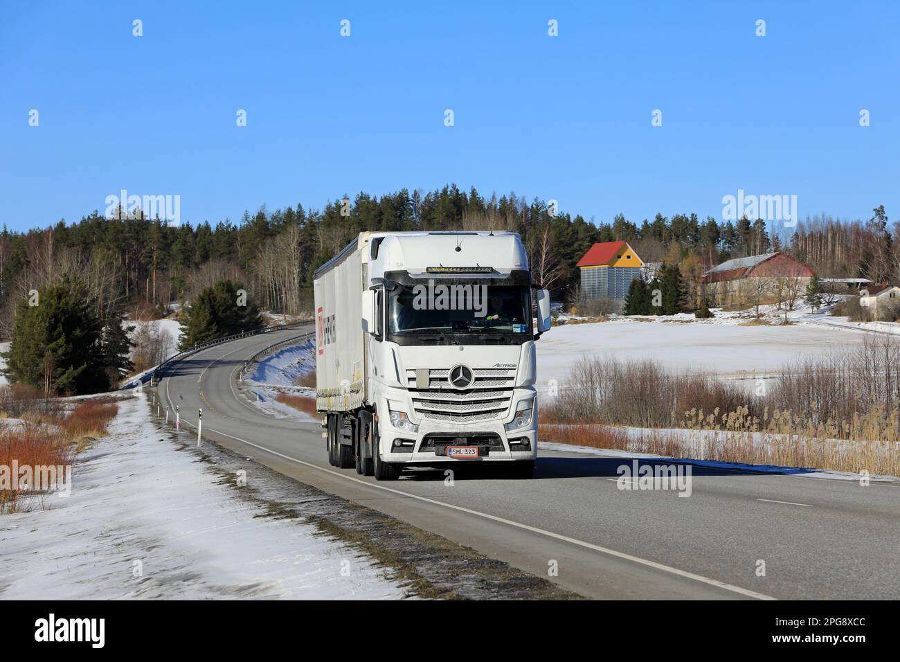 White Mercedes-Benz Actros 2653 truck pulls DB Schenker semi trailer along highway on a sunny day of early spring. Salo, Finland. March 9, 2023. Stock Photo