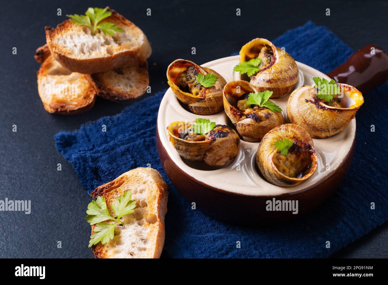 Food concept Escargots Baked French snails with Garlic butter on black