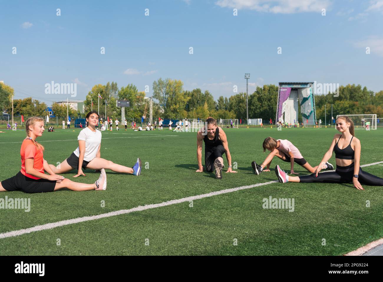 Female coach and group of children conducts a training session at the stadium outdoors Stock Photo