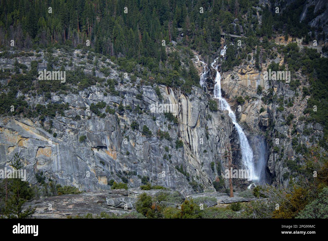 A majestic waterfall cascades down a rocky cliff, surrounded by lush ...