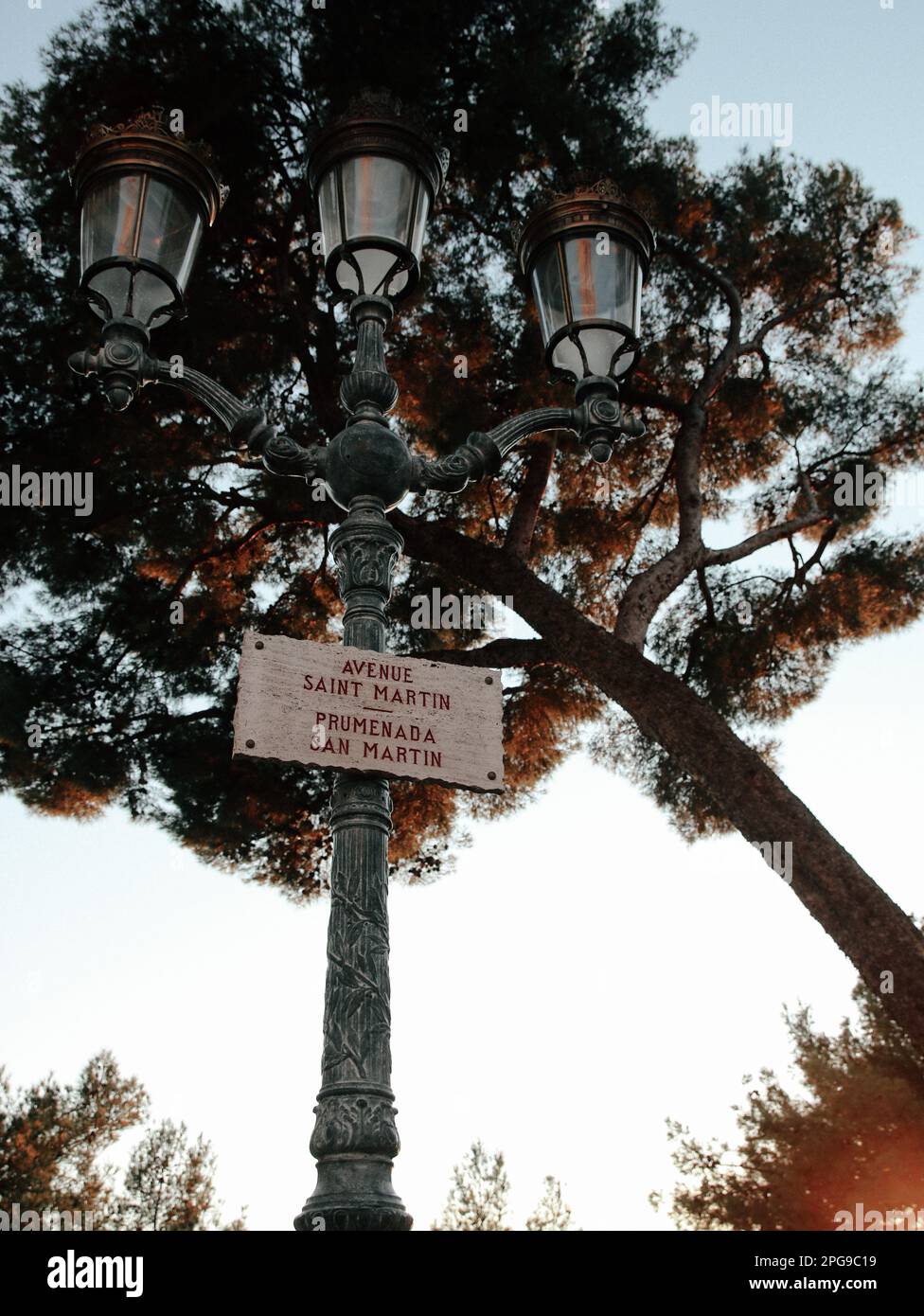 An antiquated street lamp with a sign attached to its frame, standing in a modern cityscape Stock Photo