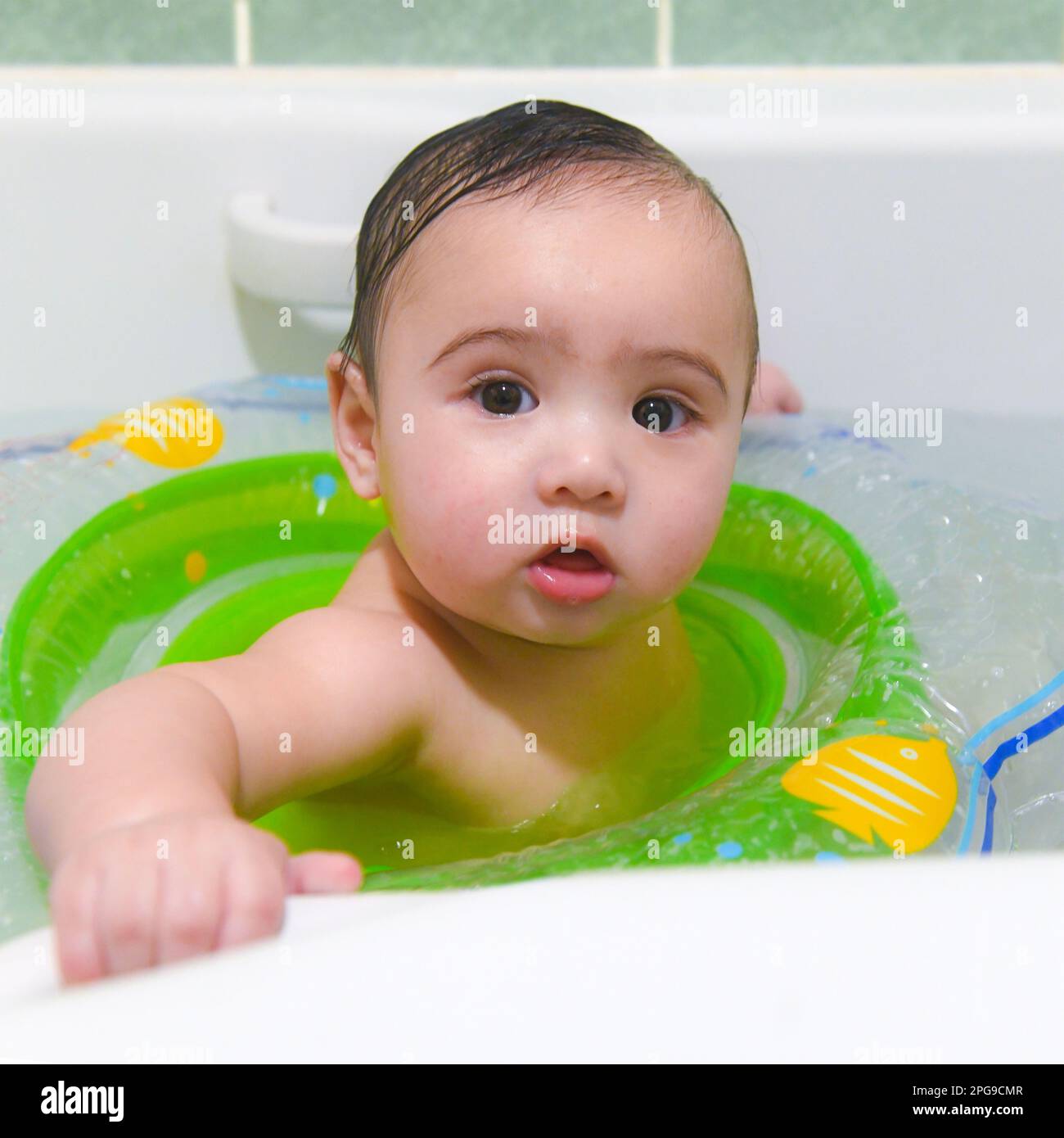 Mixed race baby 49 months playing, happy in the bath with a swimming