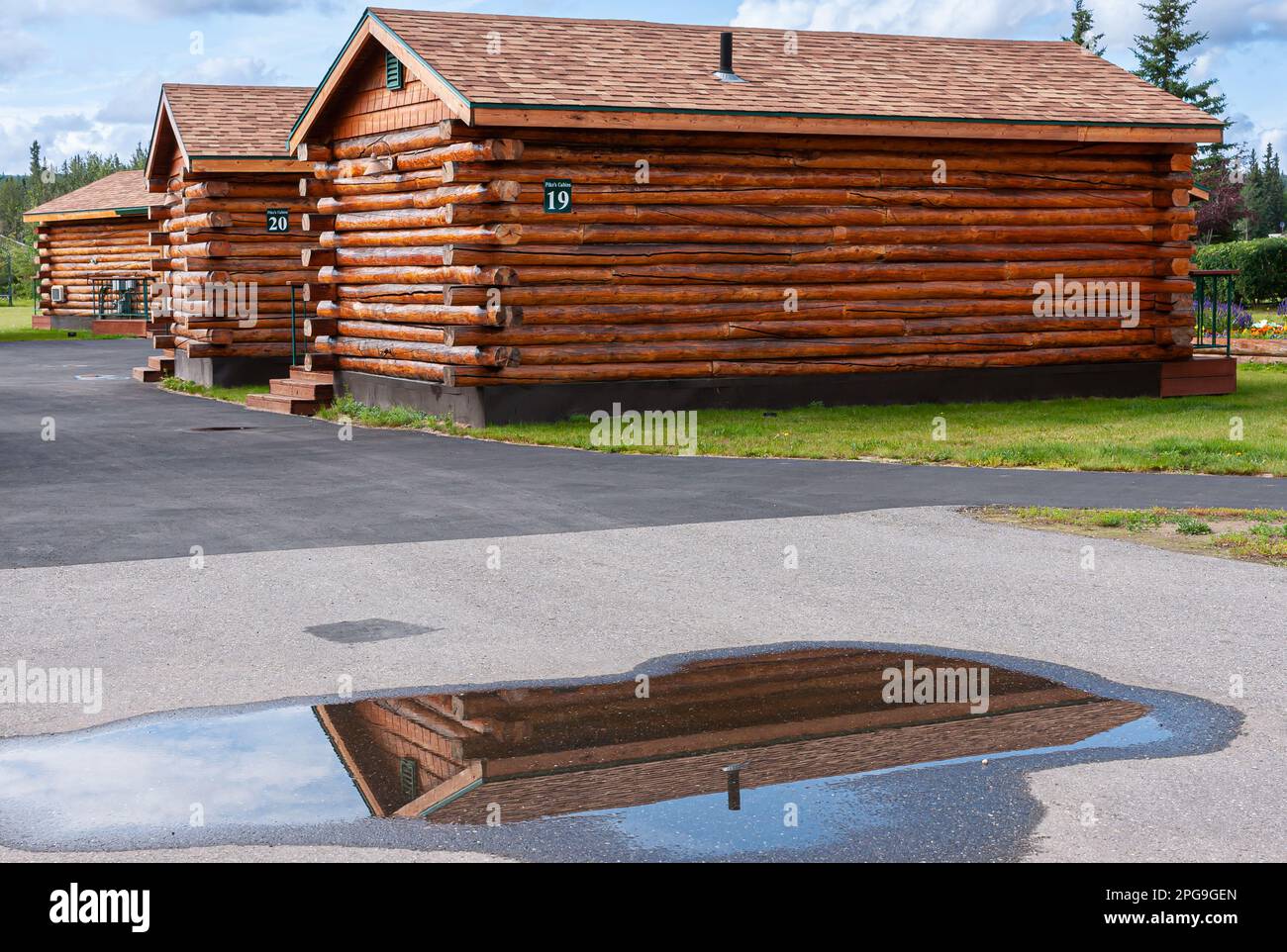 Fairbanks, Alaska, USA - July 27, 2011: Pikes Waterfront Lodge offers brown wooden small dwellings behind asphalt driveway and on green lawn. Rain poo Stock Photo