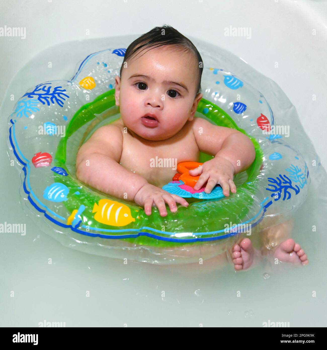 Mixed race baby 49 months, playing in the bath with a swimming float