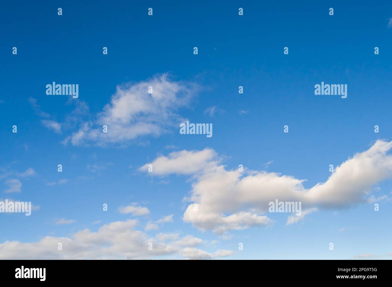 Bright blue sky background with floating cumulus clouds. Stock Photo