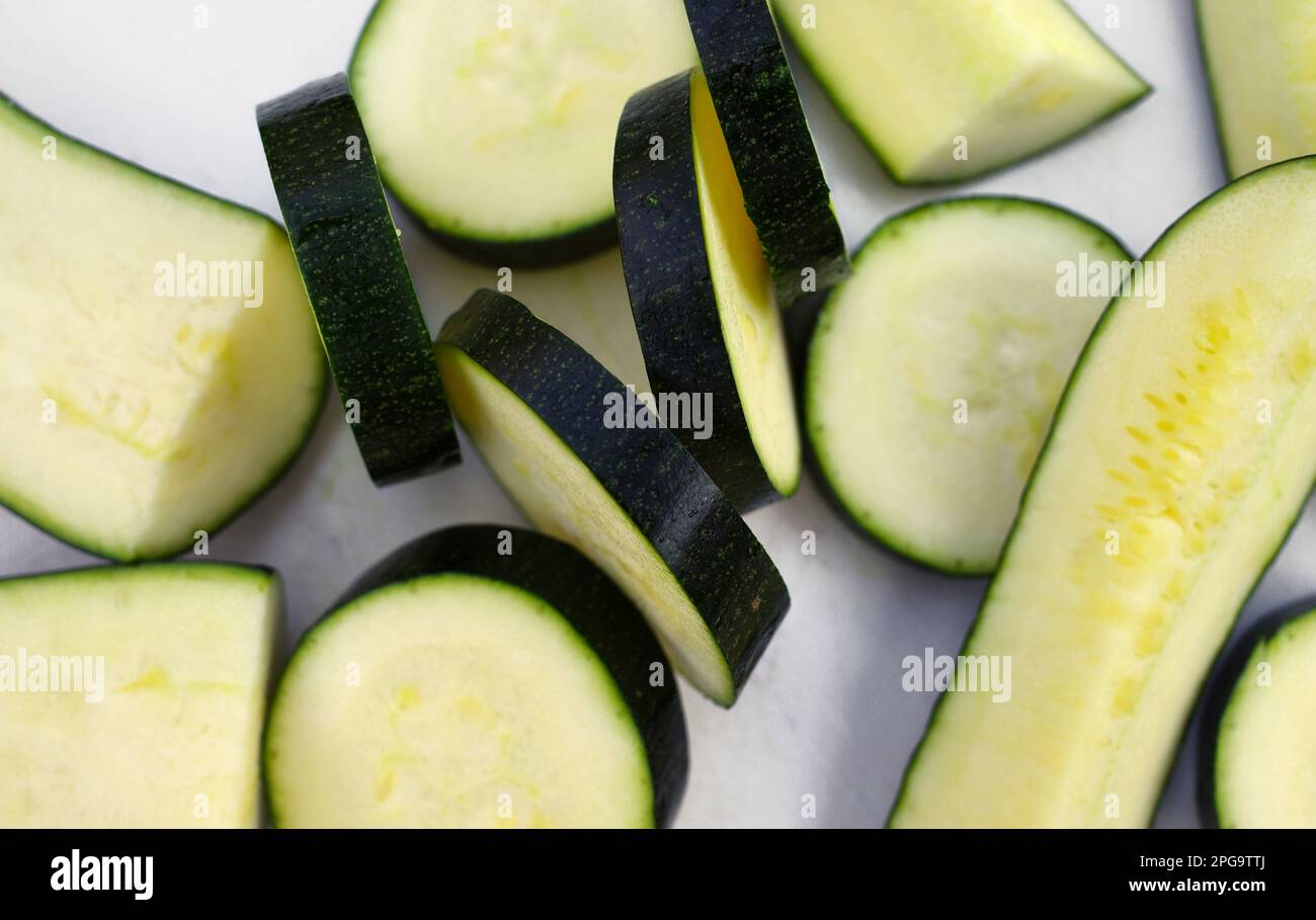 Cut zucchini, lengthwise and sliced on a white cutting board Stock Photo