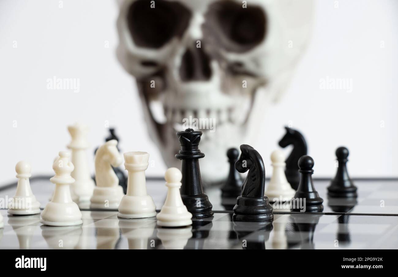 Chess board and figures on the background of the skull, a game Stock Photo