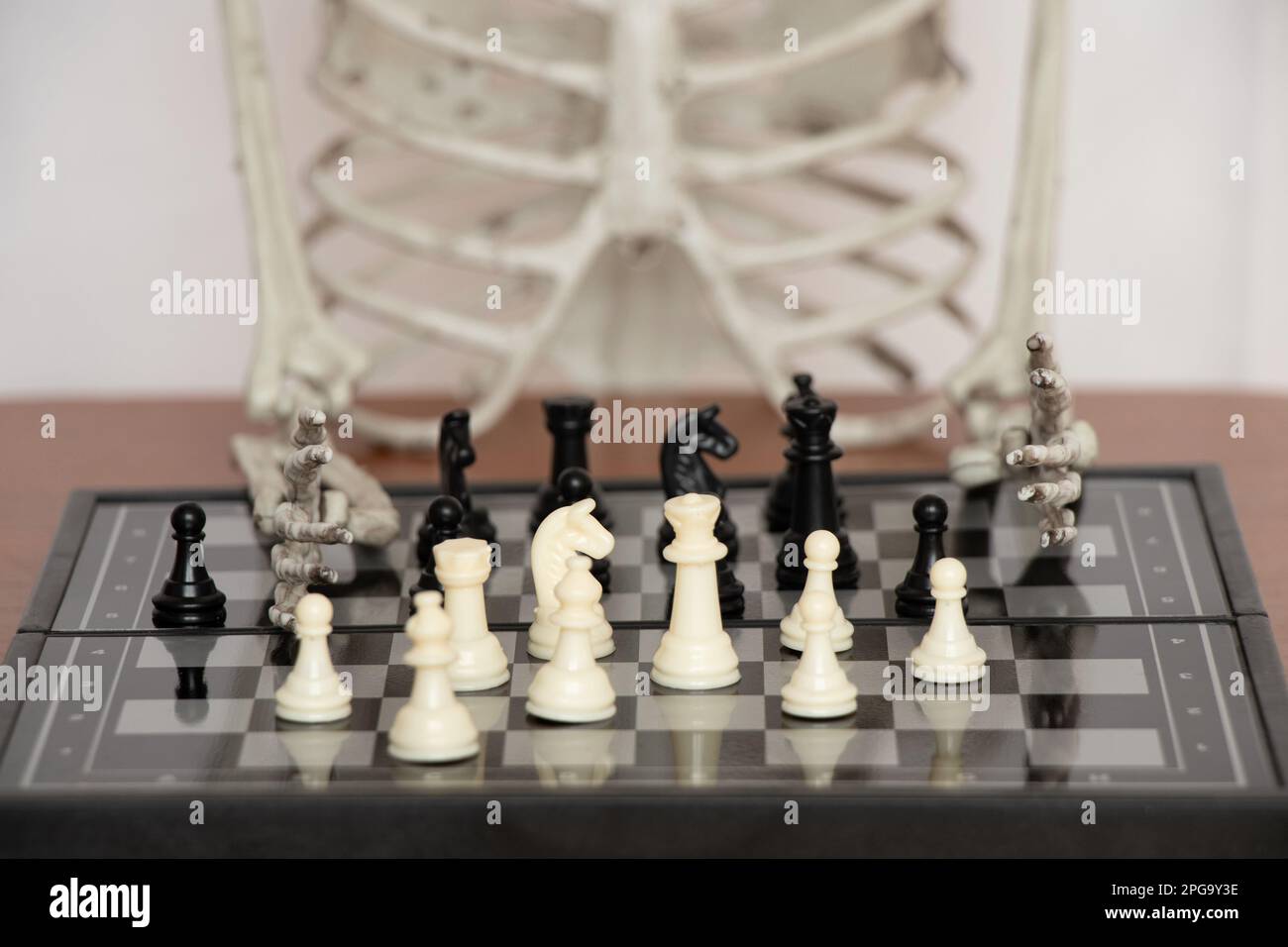 Chessboard and figures on the background of a skeleton, a game Stock Photo