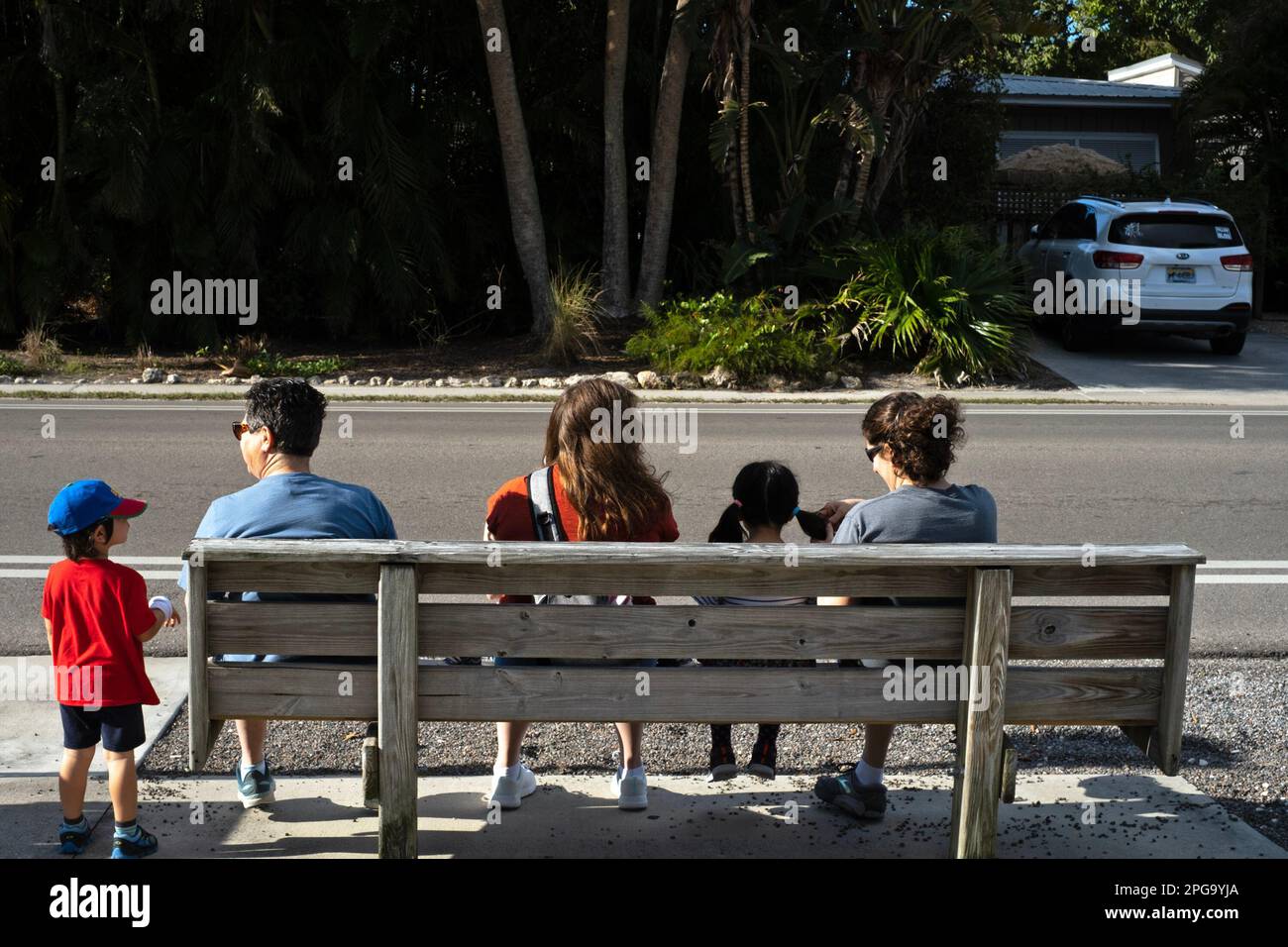 Mothers, children, and a grandmother wait for a bus to arrive. Stock Photo
