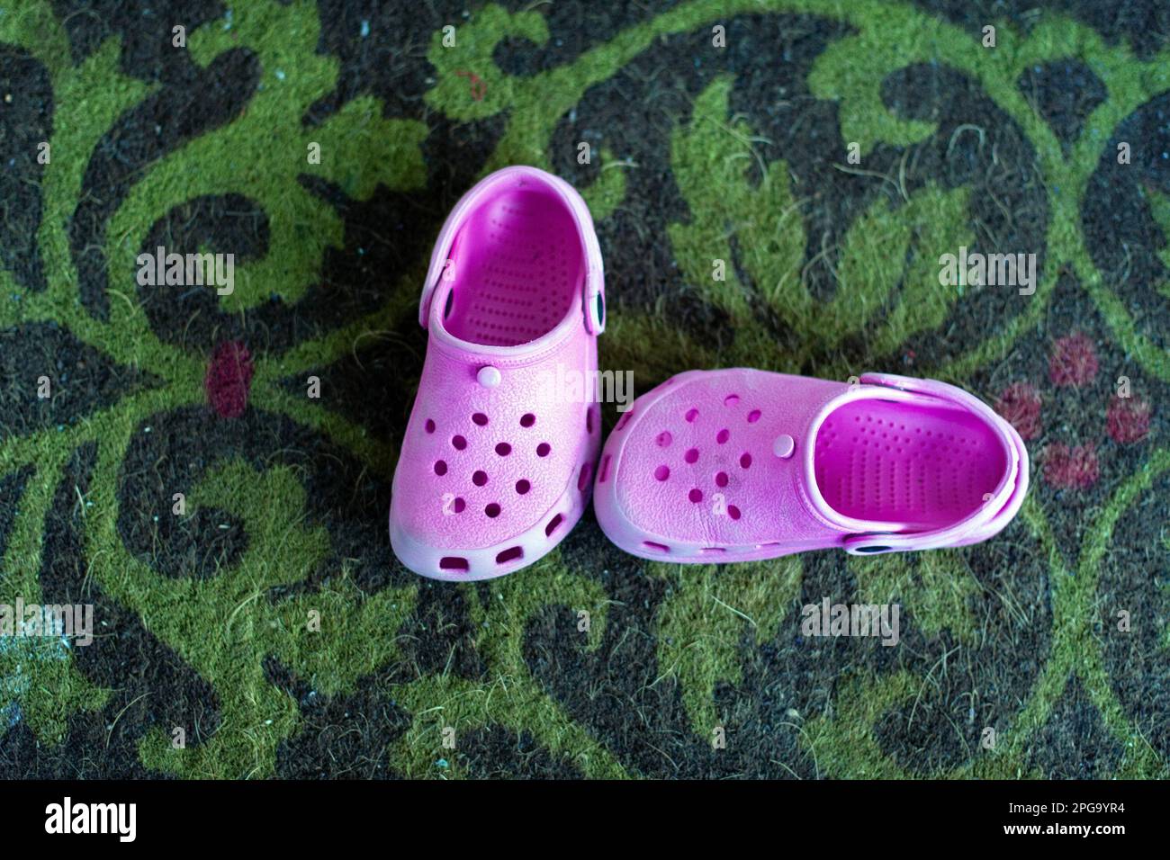 A pair of' children's Crocs sit on a carpet. Stock Photo