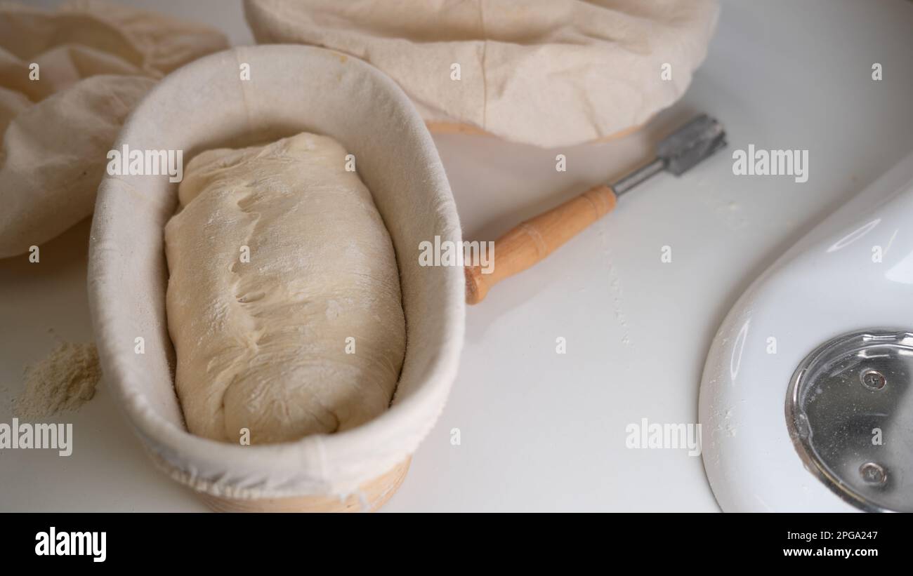Proofing basket, bread score on white table, sourdough bread