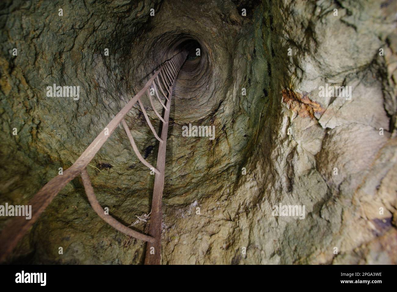 View from inside vertical stone tube downcast shaft with ladder. Stock Photo