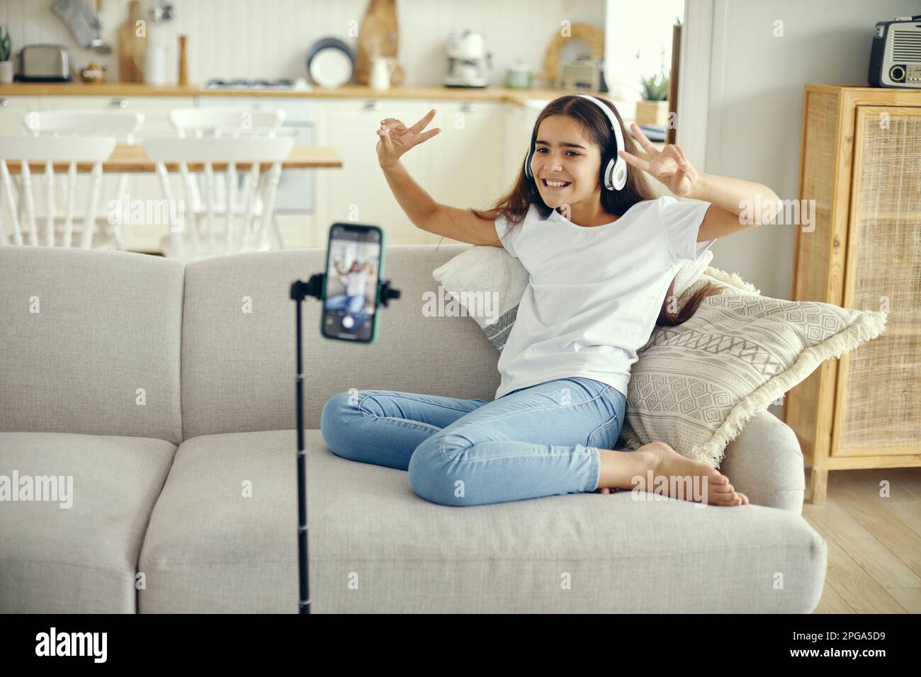 Pretty preteen girl blogger sit on sofa greeting virtual friends, record video for vlog, make