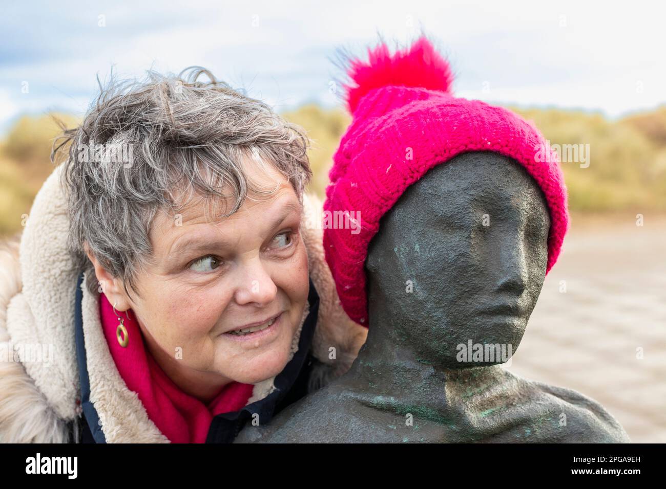 middle aged woman giving side eye to metal sculpture of person with
