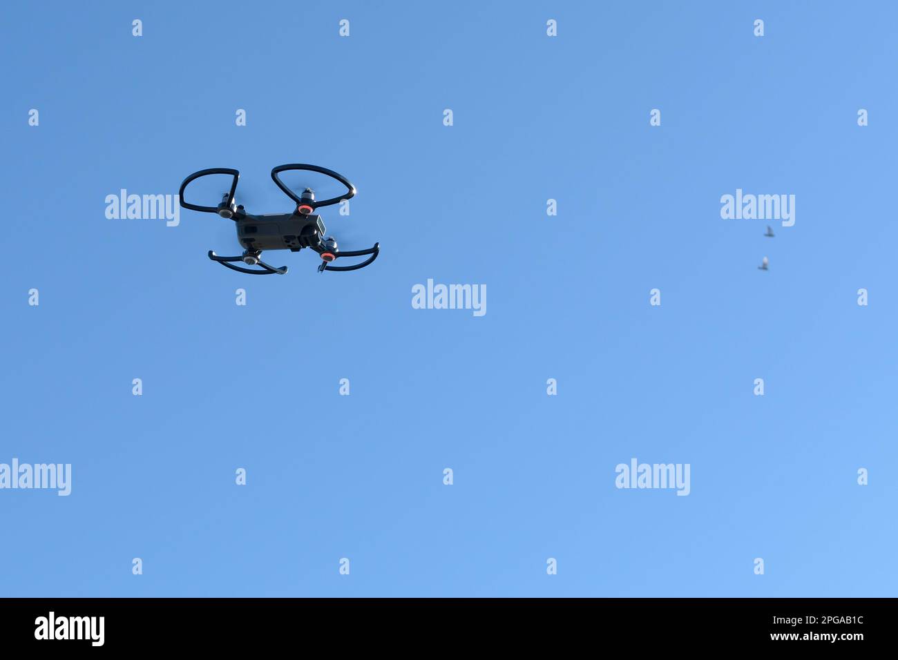 quadcopter drone flying in the blue sky, which makes photographs and video footage of the territory, Italy Stock Photo