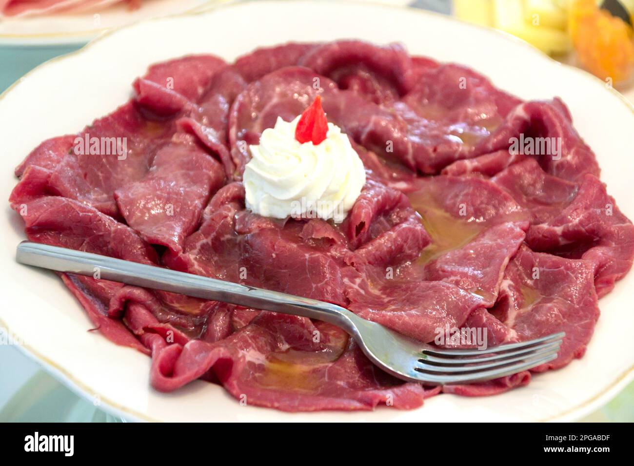 plate of raw meat slices served with oil and soft cheese Stock Photo