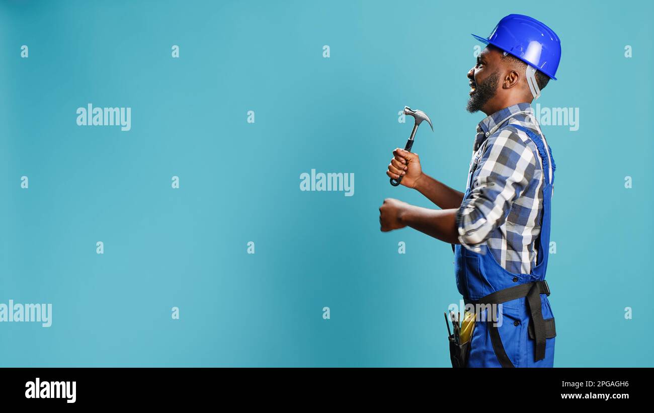 African american carpenter hitting walls with hammer, using manual ...