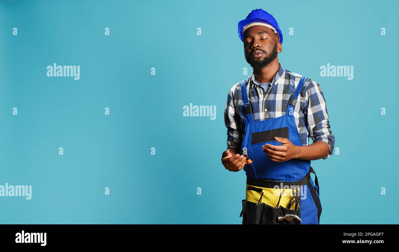 Dizzy construction worker feeling light headed in studio, almost fainting and having cartoonish stars above his head. Male contractor with hardhat being disoriented and unsteady, looney tunes. Stock Photo