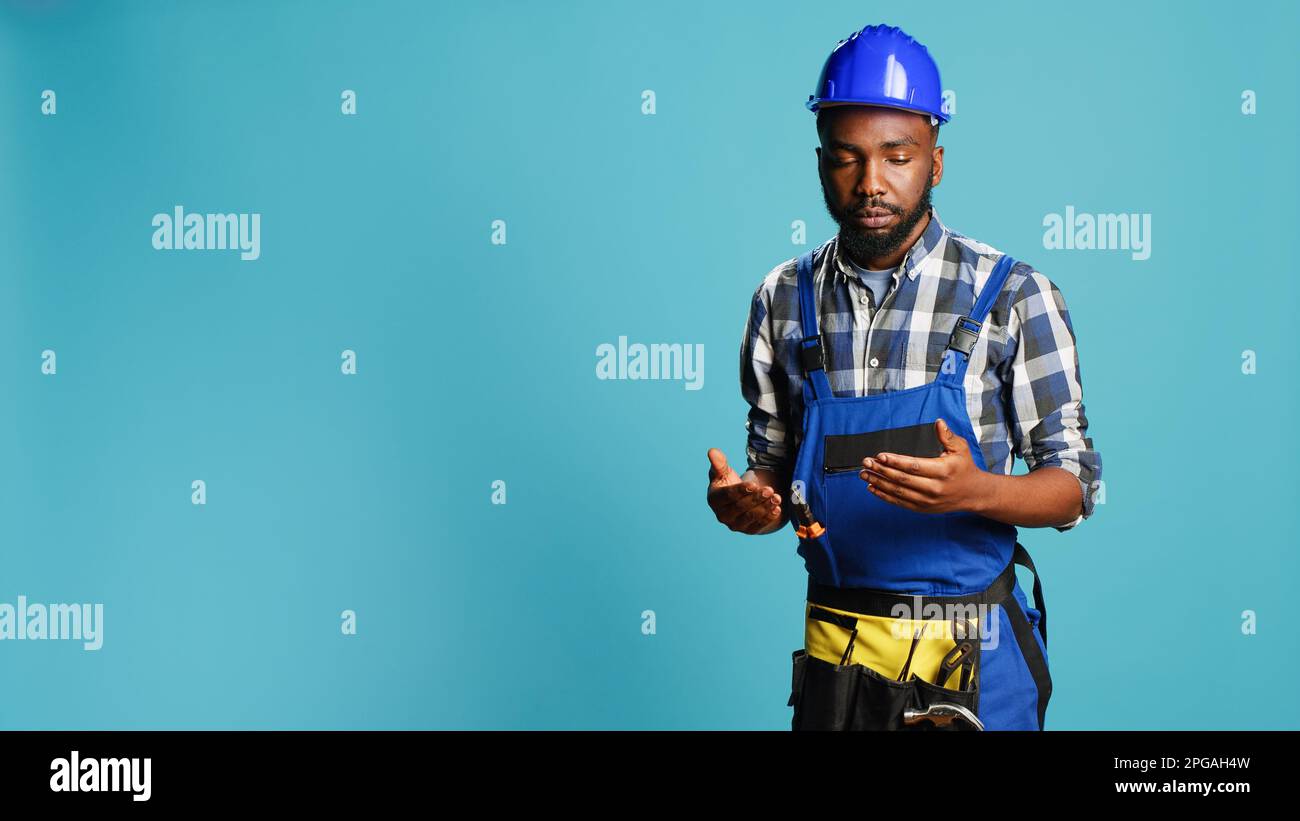 Wobbly repairman feeling light headed on camera, almost fainting and having looney tunes stars above his head. Young mechanic with protective helmet being dizzy and weak, cartoons. Stock Photo