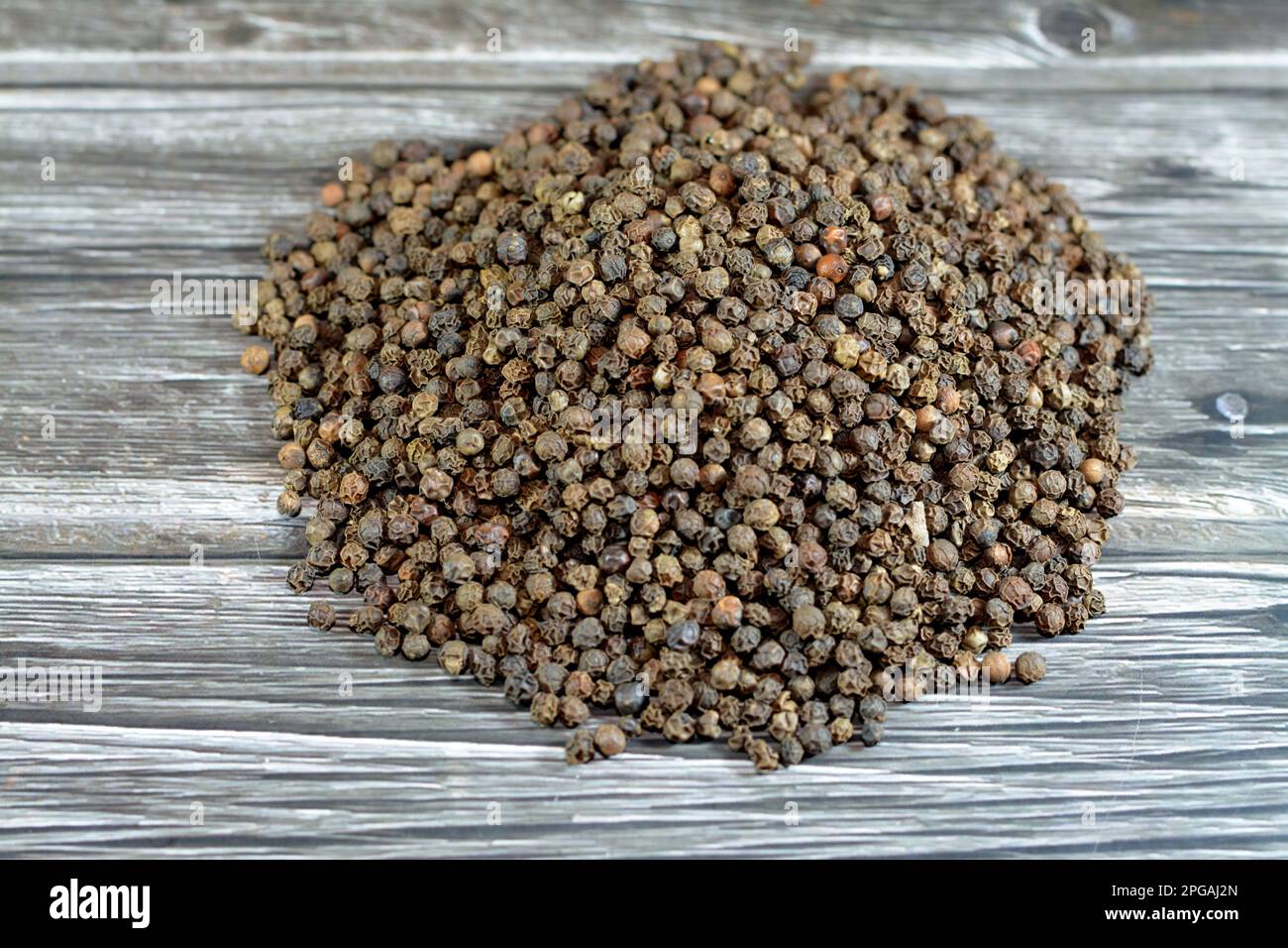 Pile of peppercorns, Black pepper (Piper nigrum), a flowering vine in the family Piperaceae, cultivated for its fruit the peppercorn, dried and used a Stock Photo
