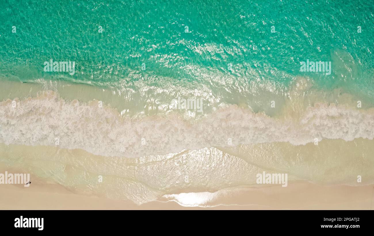 Aerial top view of ocean blue waves break on a beach. Sea waves and beautiful sand beach aerial view shot. Tropical beach with turquoise ocean water and waves, aerial view. Top view of paradise island Stock Photo