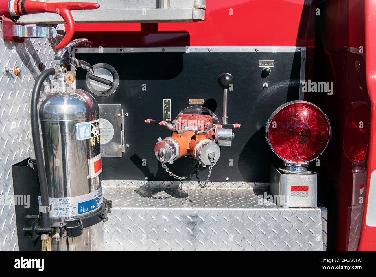 Rear of heavy duty fire truck has large water control valves and lever for connecting hoses to. Stock Photo