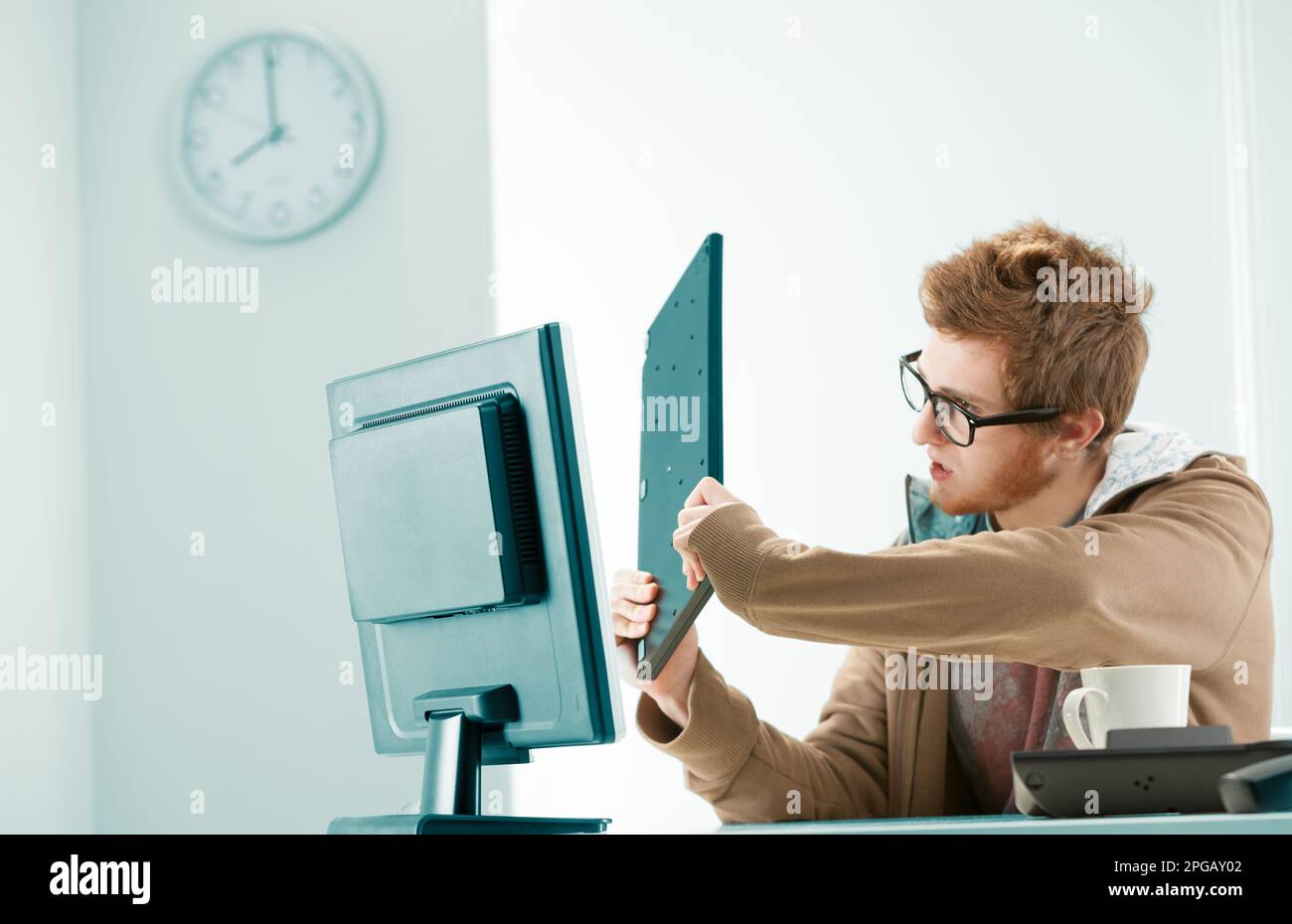 Young red-haired worker angry with his office's computer equipment ...