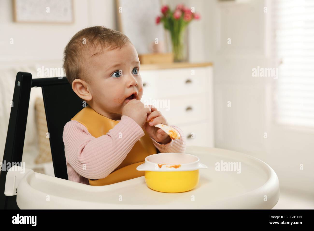 Cute little baby wearing bib while eating at home Stock Photo - Alamy